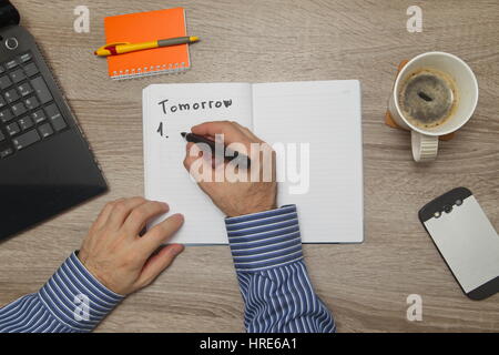 Maschio lato di scrittura di testo ' per fare" in notebook mentre come Lui beve caffè