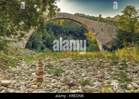 Cumulo di pietre nella parte anteriore di 500 anni hog backed Rinascimento ponte di collegamento tra due rive con singolo span in campagna italiana Foto Stock