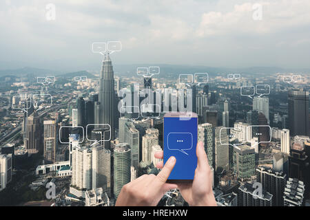 Mano azienda smartphone con uno spazio vuoto per il testo sulla città e chat di bolla per la comunicazione. Tecnologia e concetto di comunicazione Foto Stock