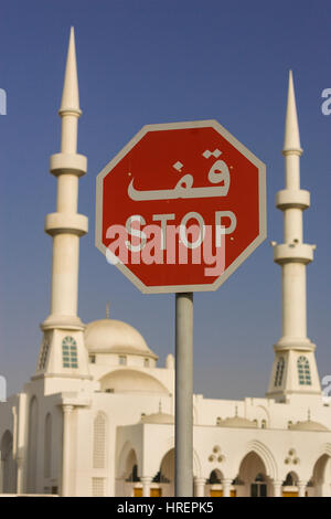 FUJAIRAH, EMIRATI ARABI UNITI - segno di stop in arabo e in inglese, nella parte anteriore della moschea. Foto Stock