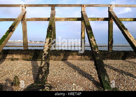 Struttura di frangionde in legno struttura sulla spiaggia di ciottoli, simmetrico shot contro il cielo blu Foto Stock