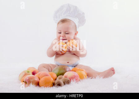 Poco happy baby in un chef hat con frutti Foto Stock