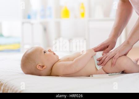 Donna facendo esercizi e massaggio il bambino indossava nel pannolino Foto Stock