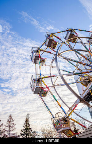 Un colorato ruota panoramica Ferris contro un nuvoloso blu del cielo della sera. Foto Stock