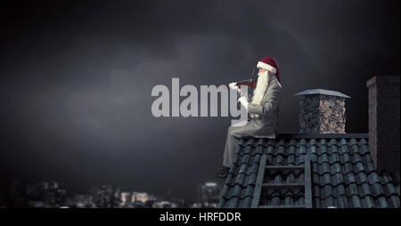 Babbo Natale sul tetto di casa suona il violino. I supporti misti Foto Stock