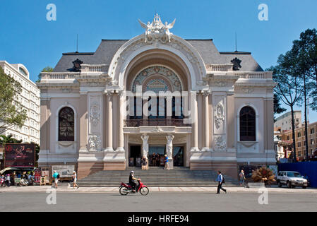 Teatro comunale in Ho Chi Minh City con la gente del posto e i turisti a piedi o alla guida in passato su un ciclomotore in una giornata di sole con cielo blu. Foto Stock