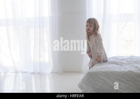 Poco adorabile bambina è alzarsi dal suo letto al mattino Foto Stock