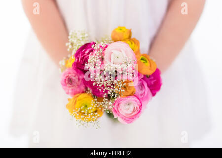 Carino bambina in abito bianco azienda ranunculus bouquet di fiori sulla festa di compleanno. Piccolo fiore ragazza al matrimonio. Bambino con fiori d'estate. Kid wi Foto Stock