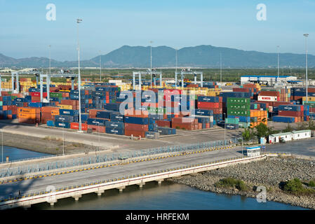 Vista aerea del Cai Mep International Terminal in Vietnam con contenitori impilati in righe in una giornata di sole con cielo blu. Foto Stock