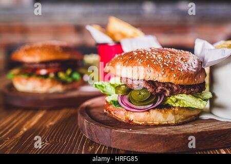 Hamburger freschi sul tavolo di legno con seconda burger in background. Foto Stock