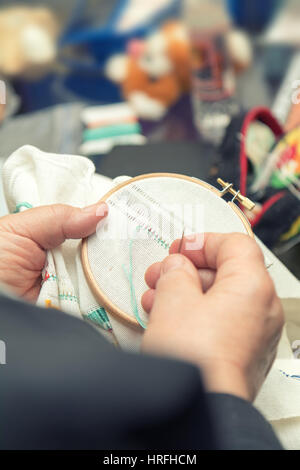 Donna mani facendo openwork ricamo su homespun biancheria. Close up. La colorazione e l'elaborazione di foto Foto Stock