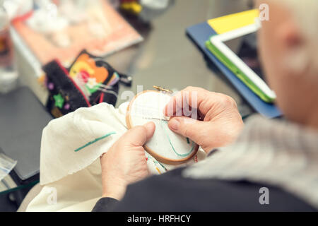 Donna mani facendo openwork ricamo su homespun biancheria. Close up. La colorazione e l'elaborazione di foto Foto Stock