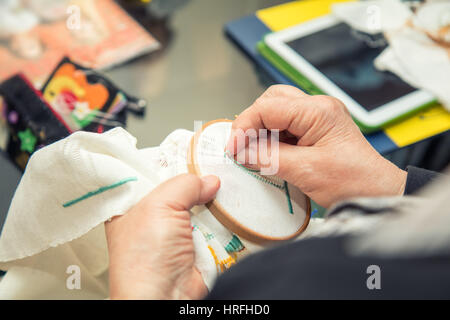 Donna mani facendo openwork ricamo su homespun biancheria. Close up. La colorazione e l'elaborazione di foto Foto Stock