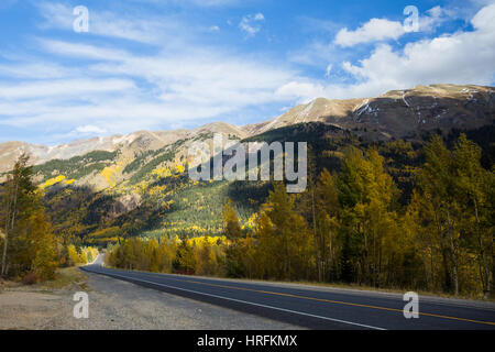 Rientrano nelle alte elevazioni del Colorado. Una strada attraversa molti alberi di Aspen e la luce della neve è già caduto sulla cime sopra i. Nuvole creare shad Foto Stock