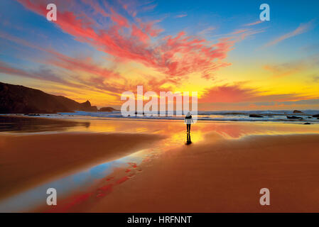 Scenic tramonto con donna che cammina sulla marea di declino beach Foto Stock