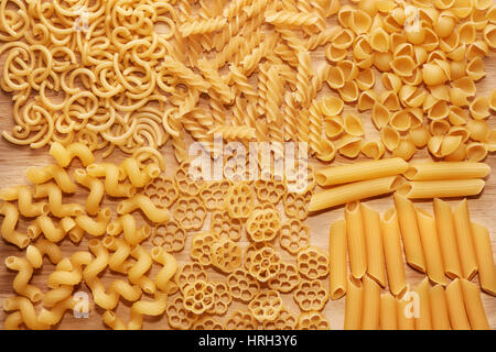 Chiudere fino a diversi tipi di pasta secca luce sul tavolo di legno, vista dall'alto Foto Stock
