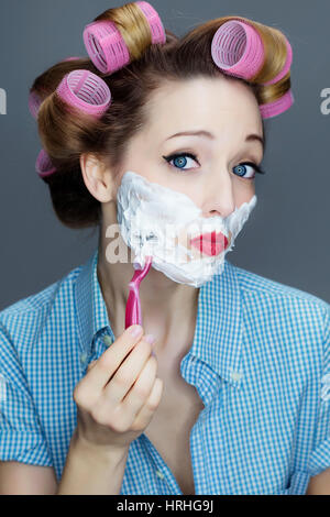 Junge Frau mit Lockenwicklern im Haar bei der Nassrasur - donna con capelli rasatura a rullo Foto Stock