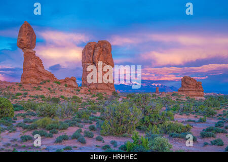 Roccia equilibrata e nuvole al tramonto, Arches National Park nello Utah, La Sal Mountains al di là Foto Stock