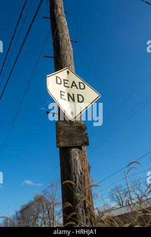 Vecchio dead end road sign su legno palo del telegrafo, blu cielo dietro. Foto Stock