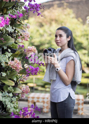 Giovane donna visualizzazione di orchidee tropicali al centro Dream, Giardino Botanico in Ocean Expo Park, Motobu, Okinawa, in Giappone Foto Stock