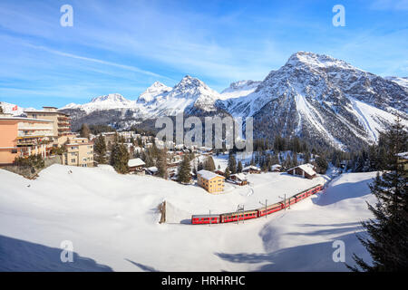 Il trenino rosso della Ferrovia Retica passa in mezzo al paesaggio innevato di Arosa, distretto di Plessur del Cantone dei Grigioni, Svizzera Foto Stock