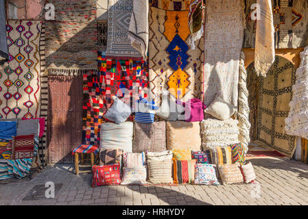 Marrakech, Marocco - 8 Dicembre 2016: Prodotti Tessili per la vendita nel famoso souk di Marrakech, Marocco, Africa. I raggi del sole sui tappeti. Foto Stock