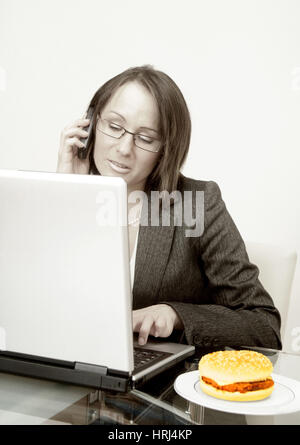 Gesch?ftsfrau arbeitet am Laptop, daneben liegt ein Burger - donna d'affari con computer portatile, a parte un Burger, Symbolfotos Foto Stock