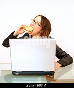 Gesch?ftsfrau bei der Arbeit am beisst Laptop in einen Burger - Business donna morsi in un burger durante l'utilizzo di laptop, Symbolfotos Foto Stock