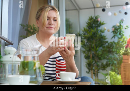 Donna che utilizza il telefono cellulare sul balcone Foto Stock