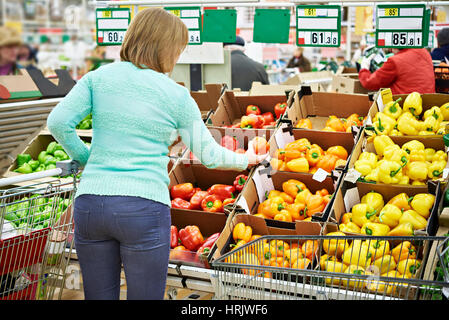 La donna acquista un peperoni in negozio Foto Stock