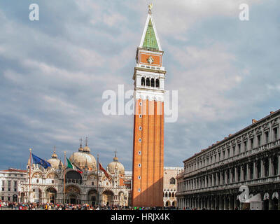 I visitatori esplorano Plazza San Marco a Venezia sotto un cielo coperto, ammirando l'architettura storica e il Campanile di San Marco . Venezia. Italia Foto Stock