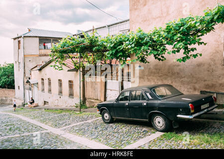 Tbilisi, Georgia - 20 Maggio 2016: la vista posteriore del Nero parcheggiata Volga GAZ, Retro rarità auto nei pressi del privato casa residenziale verde sotto il baldacchino della vite Foto Stock