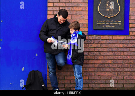Un uomo e ragazzo guardando il programma della giornata di incontri al di fuori dell'Everton Goodison Park terra Foto Stock