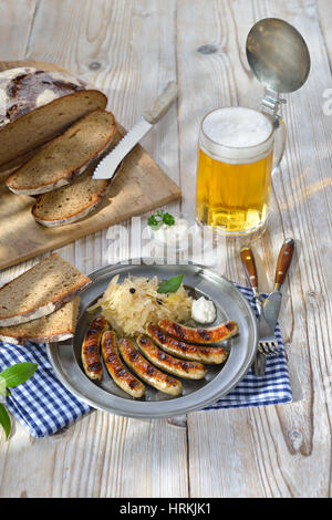 La birra bavarese pasto giardino - salsicce fritte da Norimberga con crauti e rafano tradizionalmente servite su un piatto in peltro con pane contadino Foto Stock