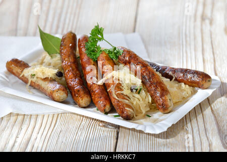 Sei fritto salsicce bavarese da Norimberga servita con i crauti su un piatto di carta Foto Stock