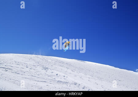 Snowboarder salto nel parco del terreno a ski resort di sole al giorno. Montagne del Caucaso, regione Dombay. Foto Stock