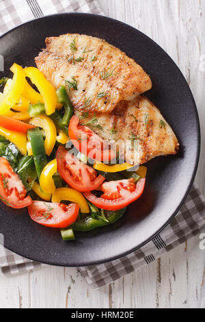 Grigliata di filetti di Tilapia e fresca insalata di verdure su una piastra di close-up. vista verticale da sopra Foto Stock
