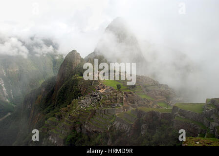 Guardando verso il basso in vista iconica del Machu Picchu con nebbia pesante e molto pochi turisti. Perù Foto Stock