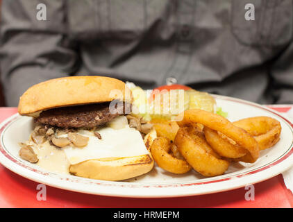 Specialty burger con funghi e formaggio svizzero e agli anelli di cipolla come un lato Foto Stock