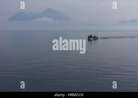 Piccola barca riempito con legna da ardere la mattina presto con la nebbia sul Lago Maggiore, Lago Maggiore, Stresa, Italia Foto Stock