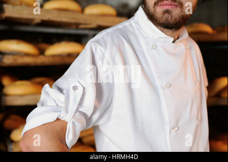 Ragazzo con la barba in un grembiule bianco sullo sfondo panificio Foto Stock