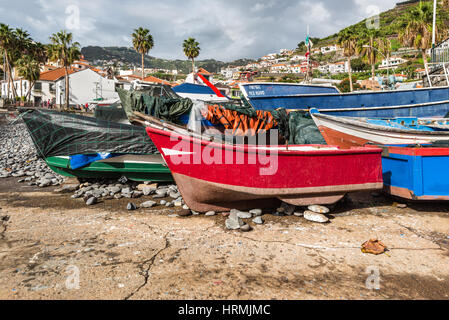 Camara de Lobos, Madeira, Portogallo - 10 dicembre 2016: barche da pesca elaborata sulla spiaggia e uno scalo a Camara de Lobos in Isola di Madeira, Portogallo. Foto Stock