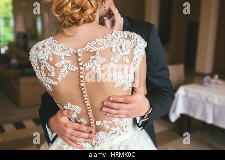 Mano di sposo abbraccia delicatamente la sposa cintola, irriconoscibile close-up Foto Stock