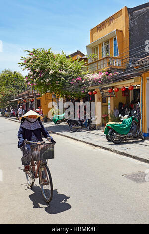 La donna corse in bicicletta in antica città di Hoi An. Quang Nam Provincia, Vietnam. Foto Stock