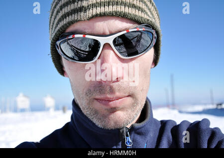 Ritratto di un giovane uomo con occhiali da sole in inverno Foto Stock