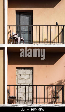 Sedie sul balcone di derelitti blocco di appartamenti in Spagna. Porta murata Foto Stock
