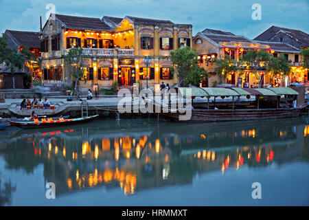 Edifici illuminati nella antica città di Hoi An riflessa in Thu Bon river di notte. Quang Nam Provincia, Vietnam. Foto Stock