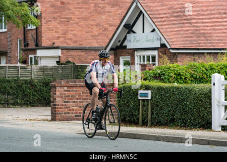 Ciclista nel salire al di sopra di equitazione sportiva attraverso Pulford vicino a Chester Foto Stock