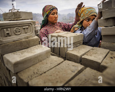 Bagmati, Sviluppo Centrale Regione, Nepal. 3 Mar, 2017. Carico dei lavoratori mattoni in confezioni per portarli in un forno ad una fabbrica di mattoni in Bagmati, vicino a Bhaktapur. Ci sono quasi 50 fabbriche di mattoni nella valle vicino a Bagmati. Il mattone maker sono molto occupato facendo mattoni per la ricostruzione di Kathmandu, Bhaktapur e di altre città della valle di Kathmandu che sono stati gravemente danneggiati dal 2015 Nepal terremoto. Le fabbriche di mattoni sono stati nella zona di Bagmati per secoli perché l'argilla locale popolare è un materiale grezzo per la posa in opera dei mattoni. La maggior parte dei lavoratori nelle fabbriche di mattoni sono lavoratori migranti wo Foto Stock