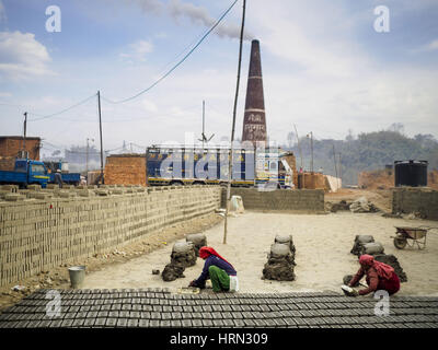 Bagmati, Sviluppo Centrale Regione, Nepal. 3 Mar, 2017. Lavoratori utilizzano stampi per formare i mattoni di argilla ad una fabbrica di mattoni in Bagmati, vicino a Bhaktapur. I mattoni saranno lay out per uno o due giorni e poi prese per il forno (il fumaiolo in background per la cottura. Ci sono quasi 50 fabbriche di mattoni nella valle vicino a Bagmati. Il mattone maker sono molto occupato facendo mattoni per la ricostruzione di Kathmandu, Bhaktapur e di altre città della valle di Kathmandu che sono stati gravemente danneggiati dal 2015 Nepal terremoto. Le fabbriche di mattoni sono stati nella zona di Bagmati per secoli perché la loca Foto Stock